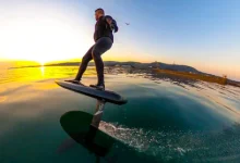 A sleek carbon fiber foilboard with a hydrofoil attachment.