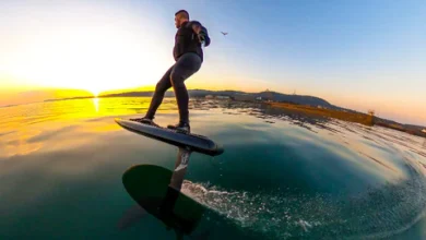 A sleek carbon fiber foilboard with a hydrofoil attachment.