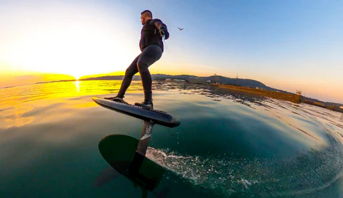 A sleek carbon fiber foilboard with a hydrofoil attachment.